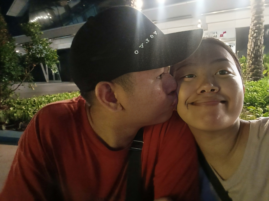 Gentle cheek kiss moment under garden lights